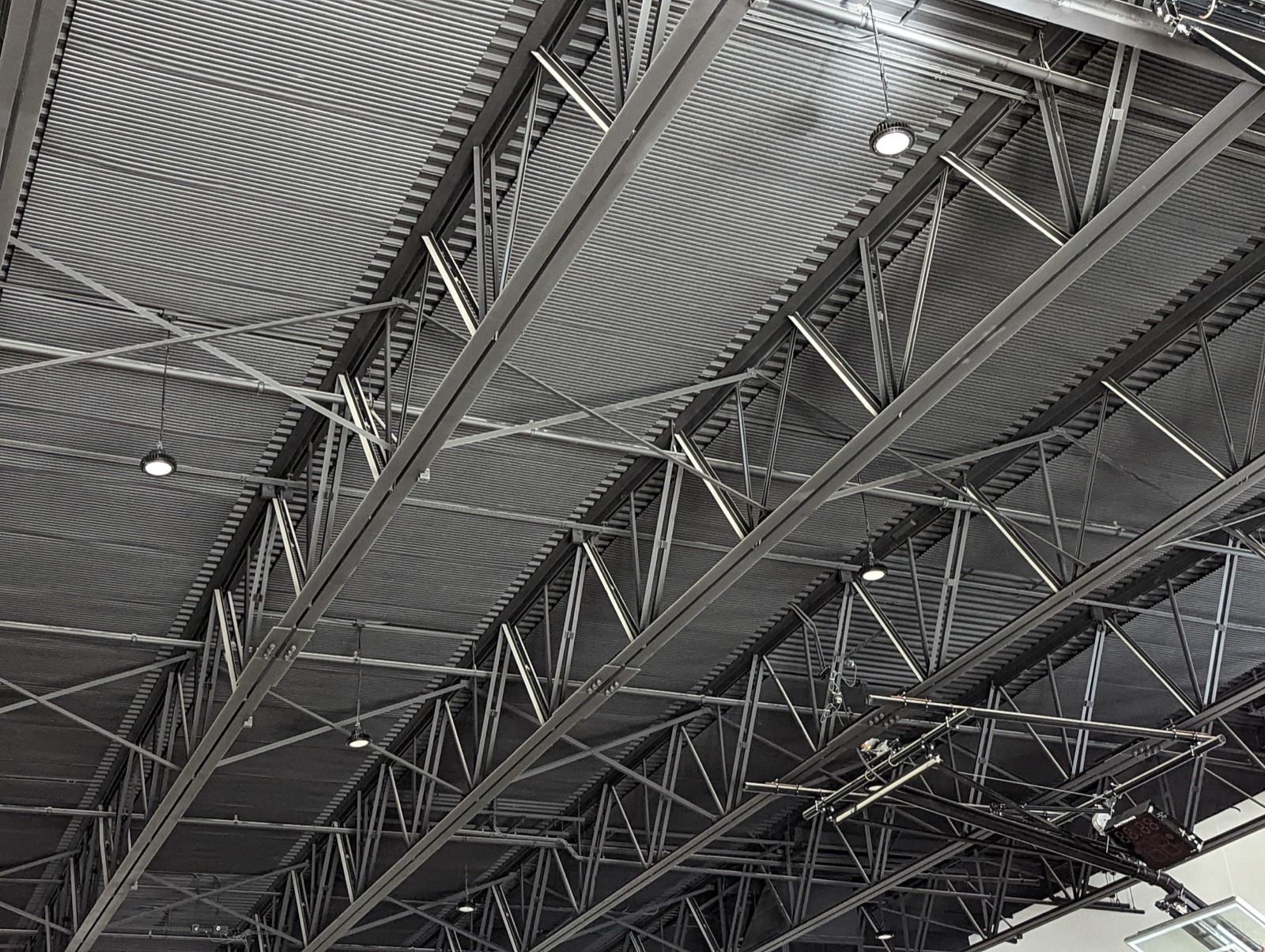Close-up of CAFETERIA corrugated recycled-PET acoustic panels mounted between the steel roof trusses